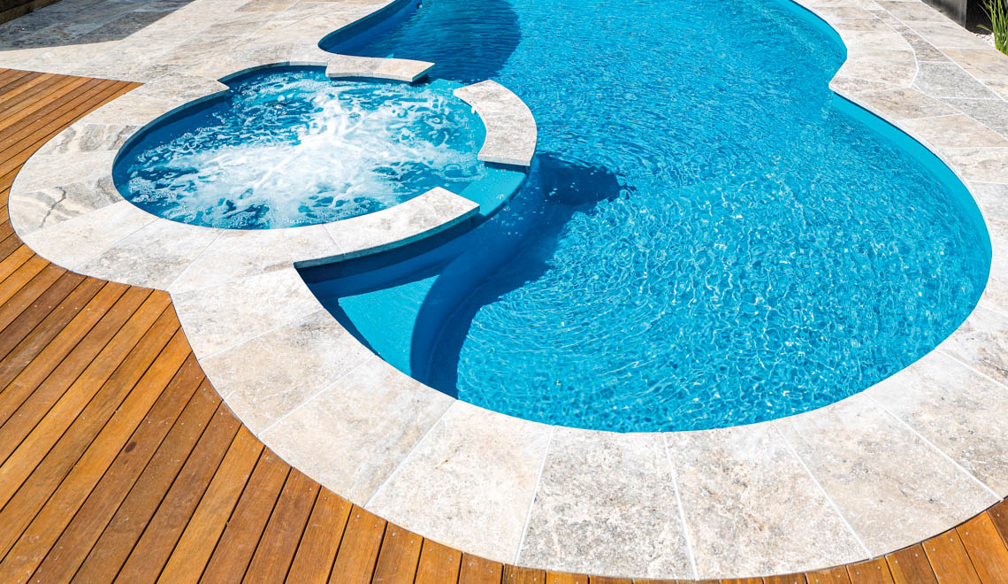 Leisure Pools Allure large freeform fiberglass swimming pool with built-in spa and splash deck