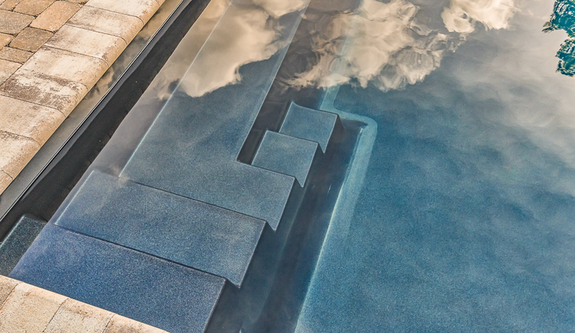 Leisure Pools Infinity composite swimming pool with built-in steps and bench