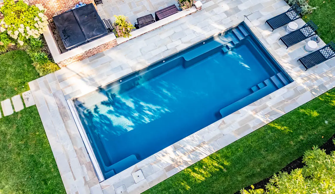 Leisure Pools Supreme inground fiberglass swimming pool with generous bench seats in Graphite Grey